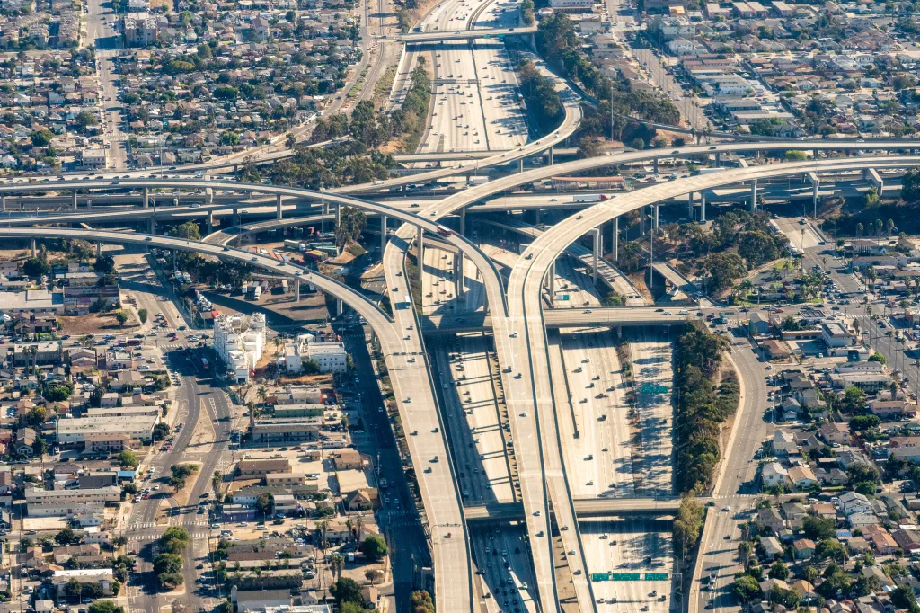 Aerial view of the Judge Harry Pregerson Interchange where the I-110 and I-105 freeways meet, surrounded by urban development in Los Angeles.