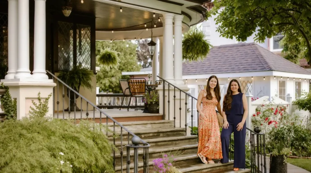 Two women standing on the steps of a porch.