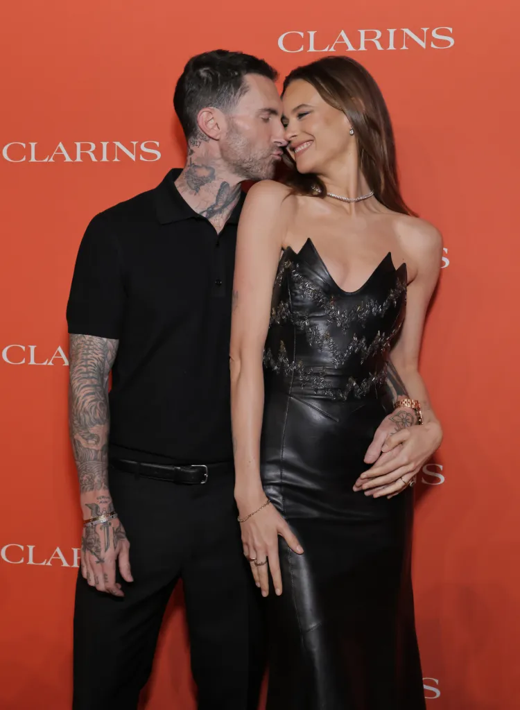 Adam Levine kissing Behati Prinsloo's cheek at an event.
