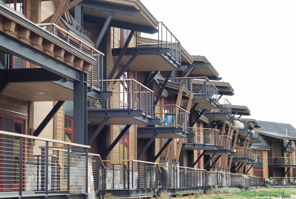 A series of balconies with metal and wood railings attached to the side of a modern residential building.