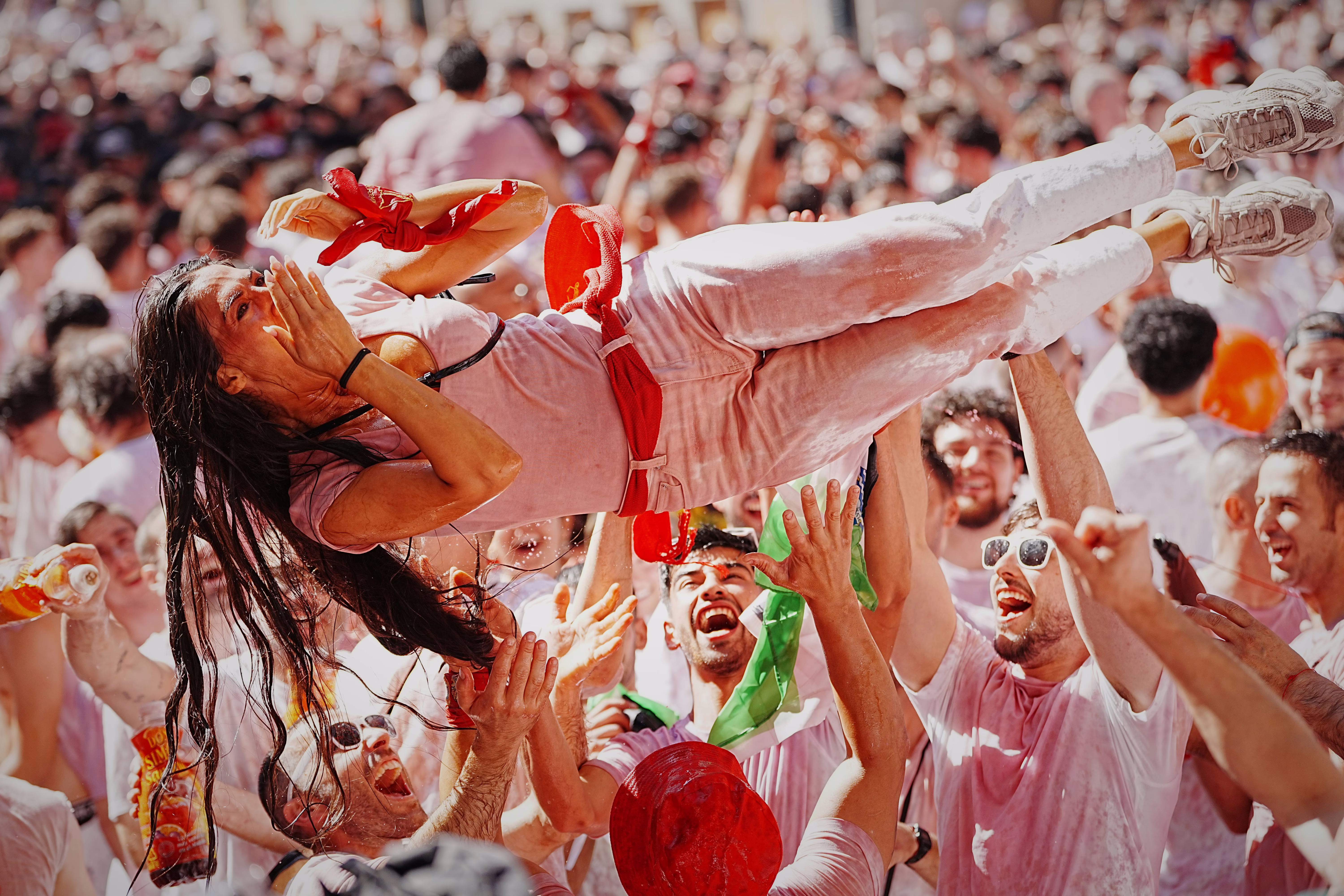 Wine-soaked revelers toss a person in the air.