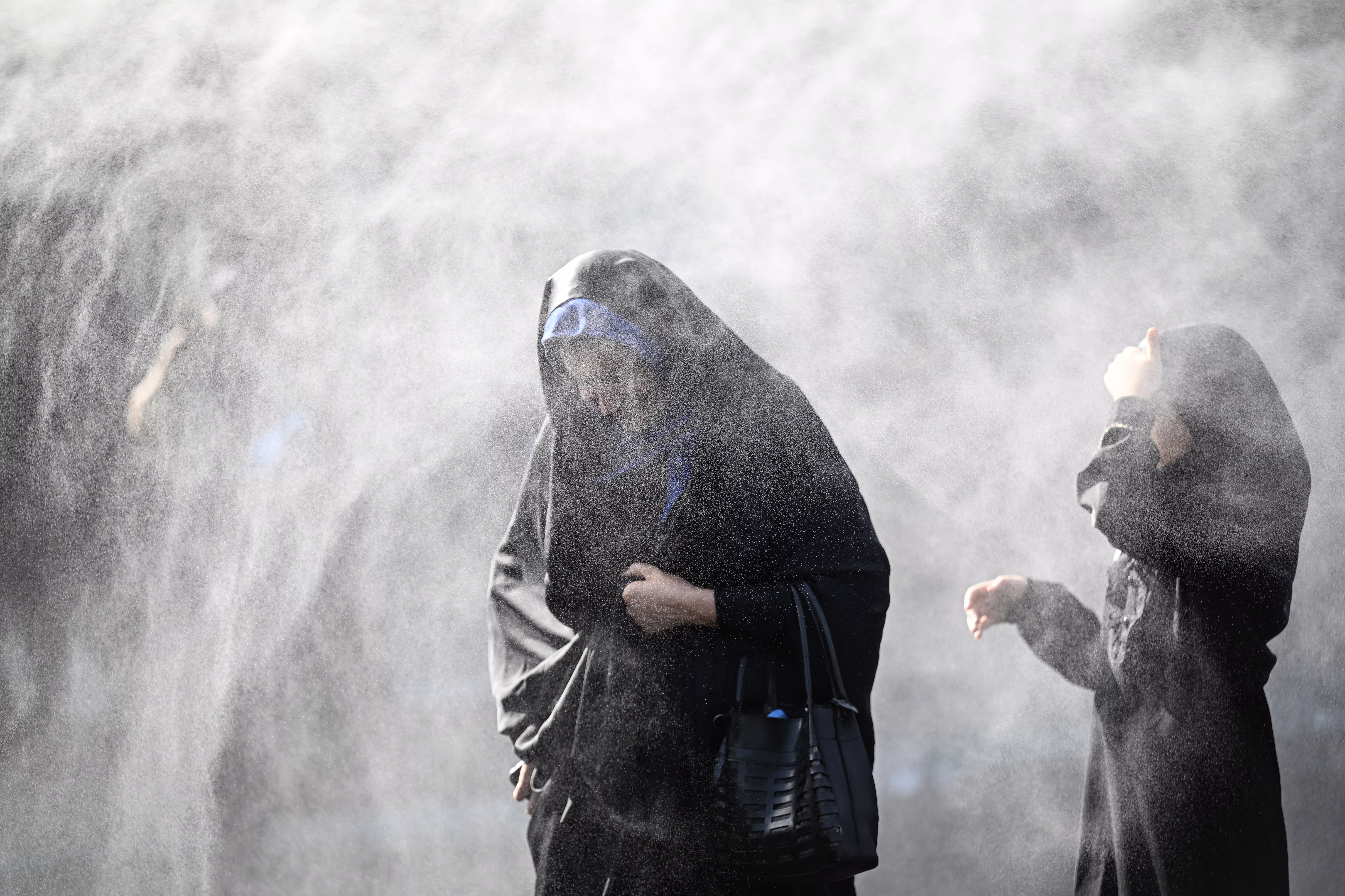 Two women walk through heavy mist on a hot day.