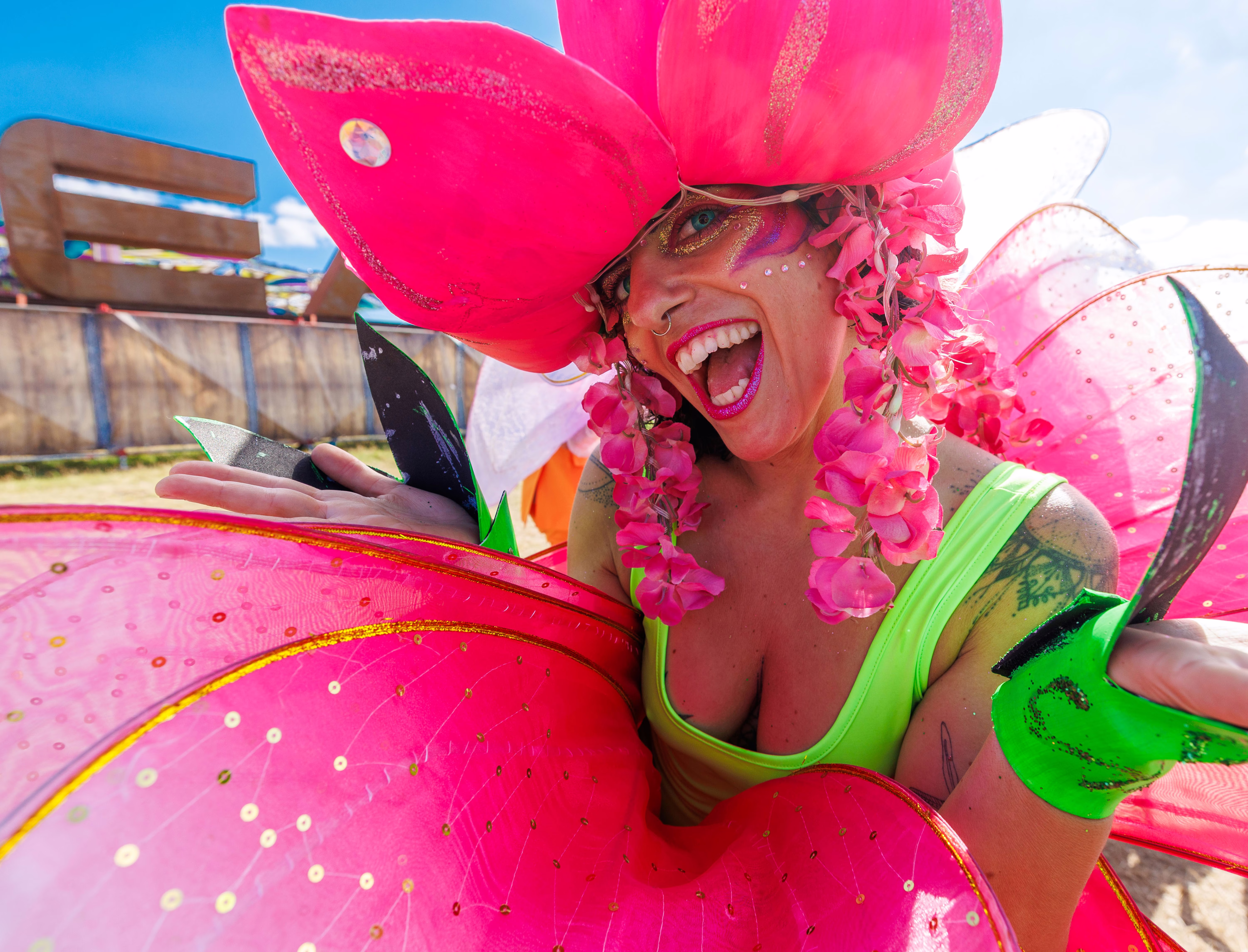 A performer in a bright pink floral costume poses with a big smile.