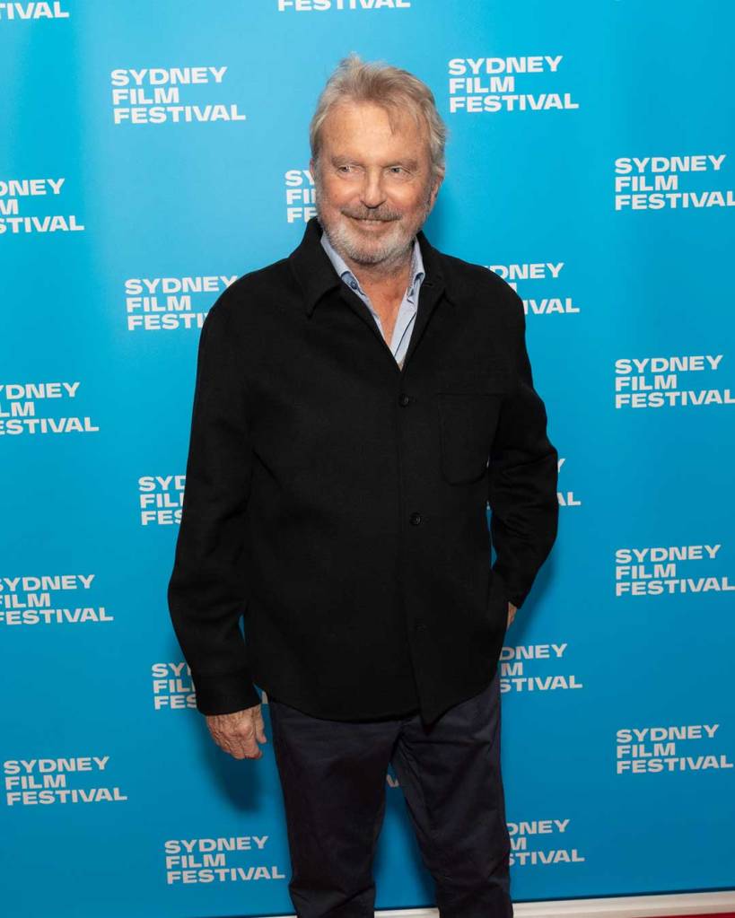 Sam Neill smiling in front of a Sydney Film Festival backdrop.