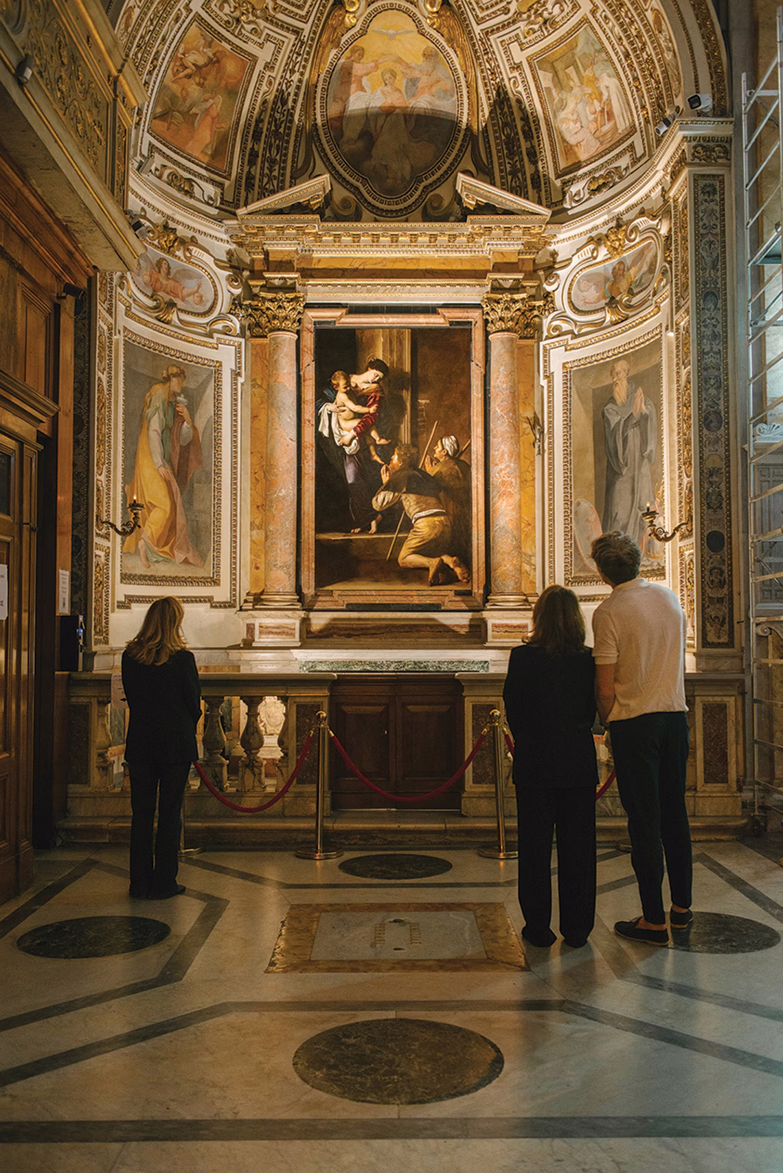 photo of several people looking at ornate chapel altar with Caravaggio painting 