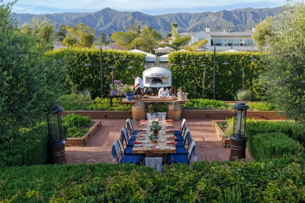 Rosewood Miramar Beach hotel outdoor dining area with a long table, pizza oven, and mountain views.