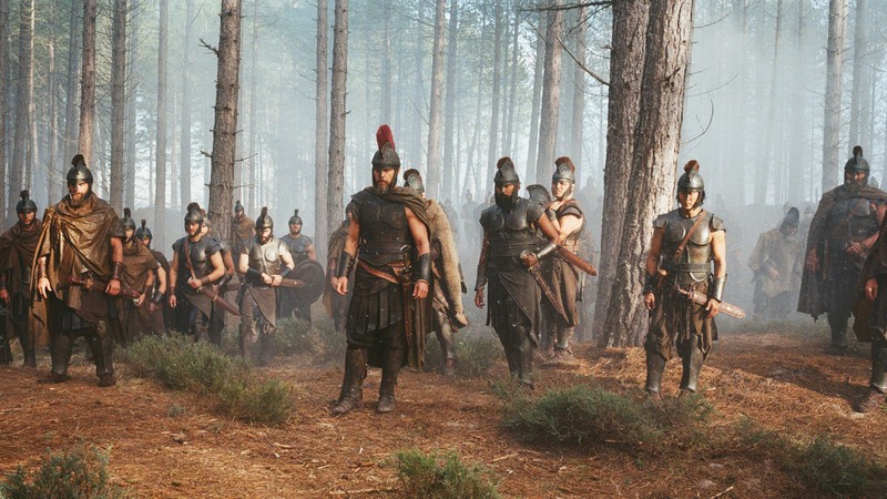 A group of men in Greek battle armor standing in the woods