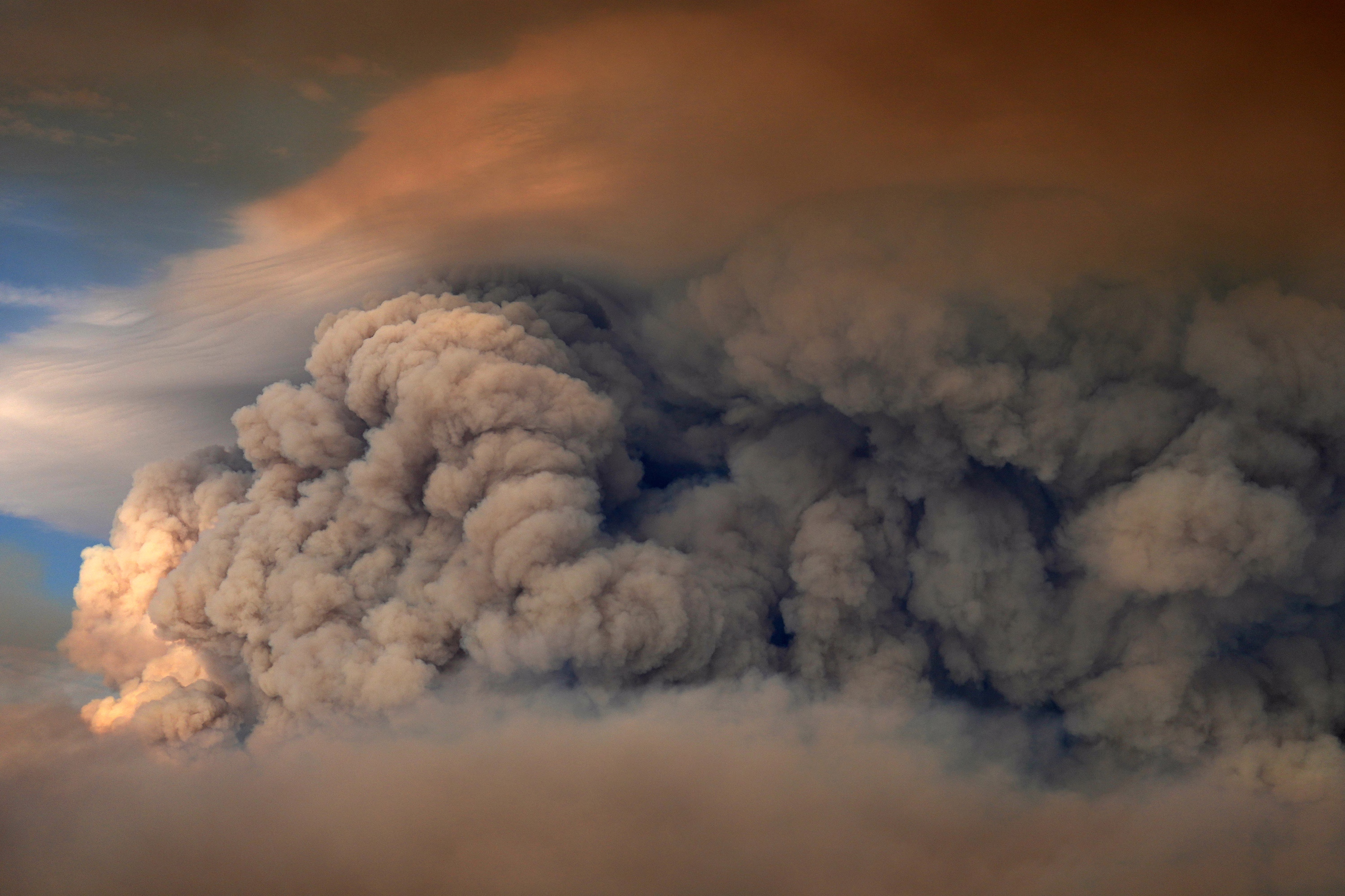 Thick plumes of smoke rise above a wildfire.