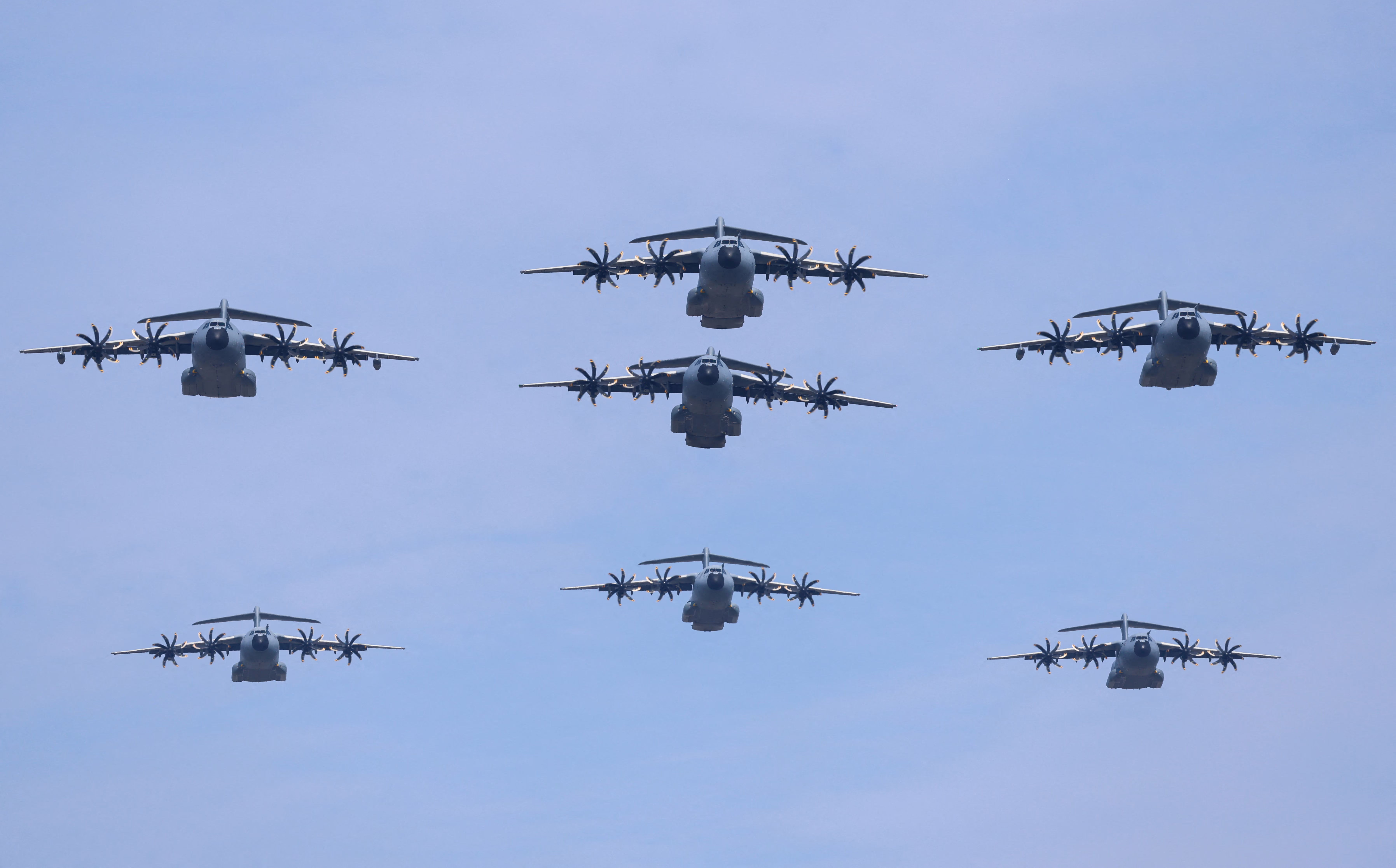 Seven large propeller-driven military aircraft fly in formation during an air show.