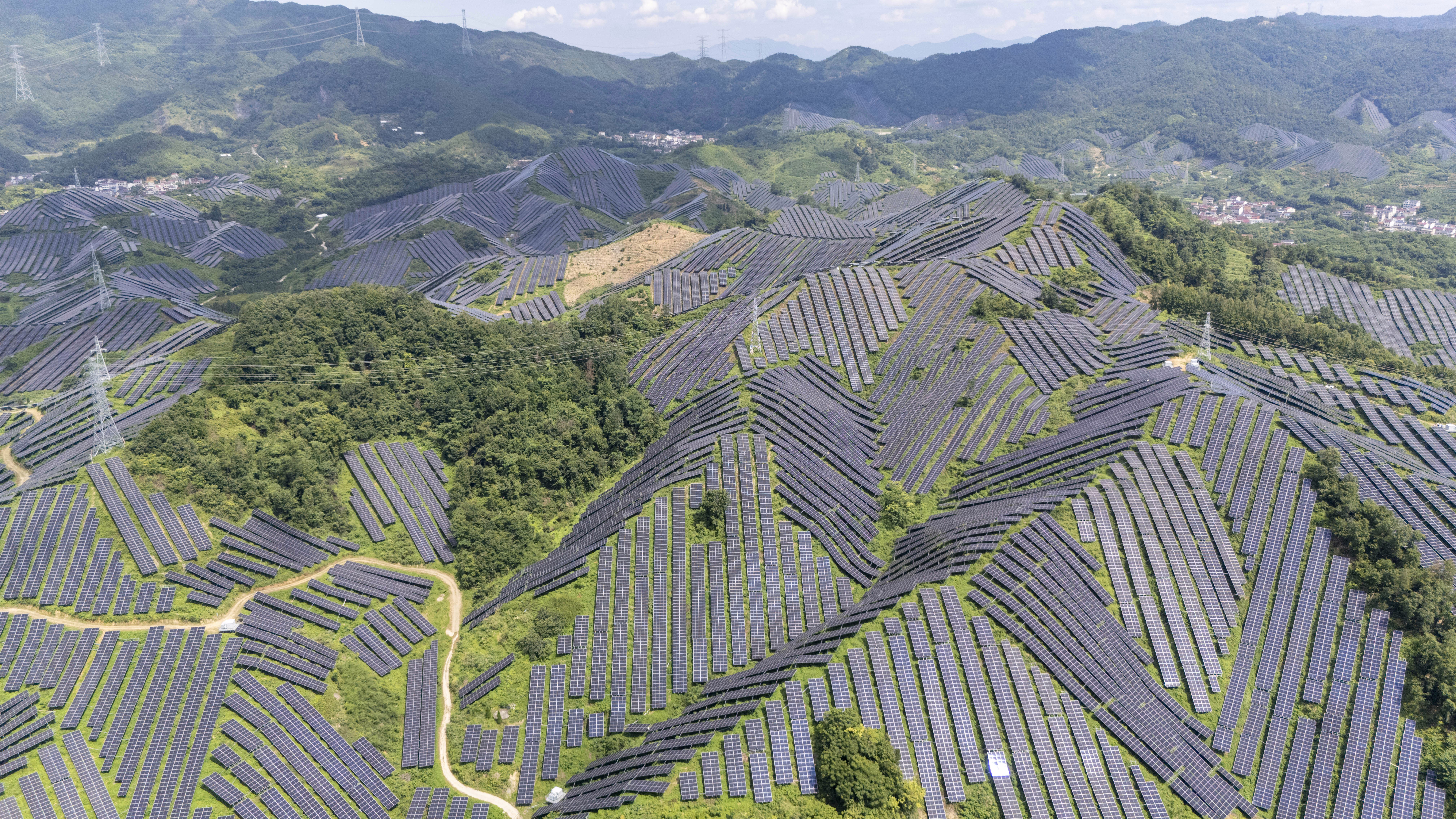 An aerial view of many rows of hillside solar panels