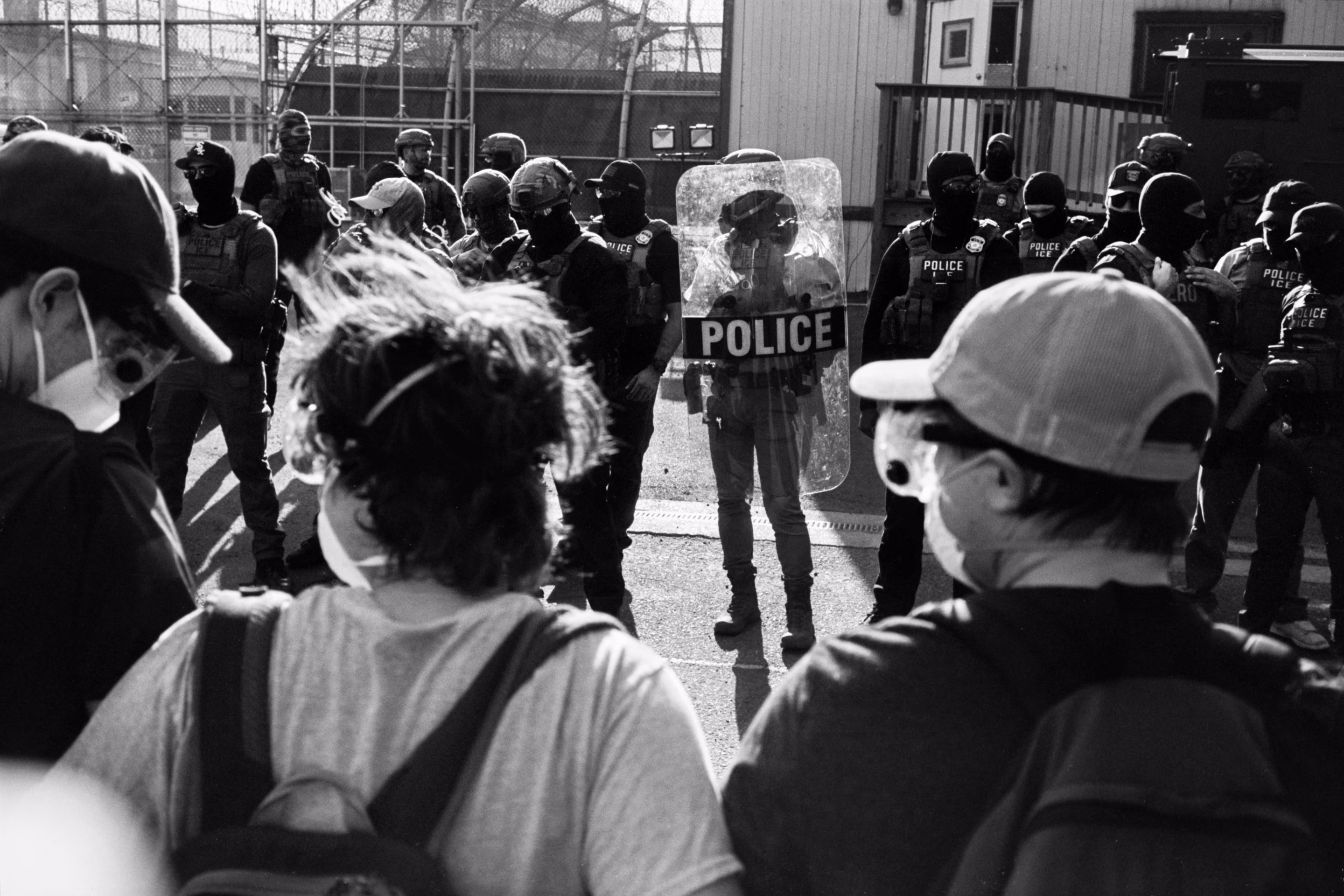 people stand in front of a line of police