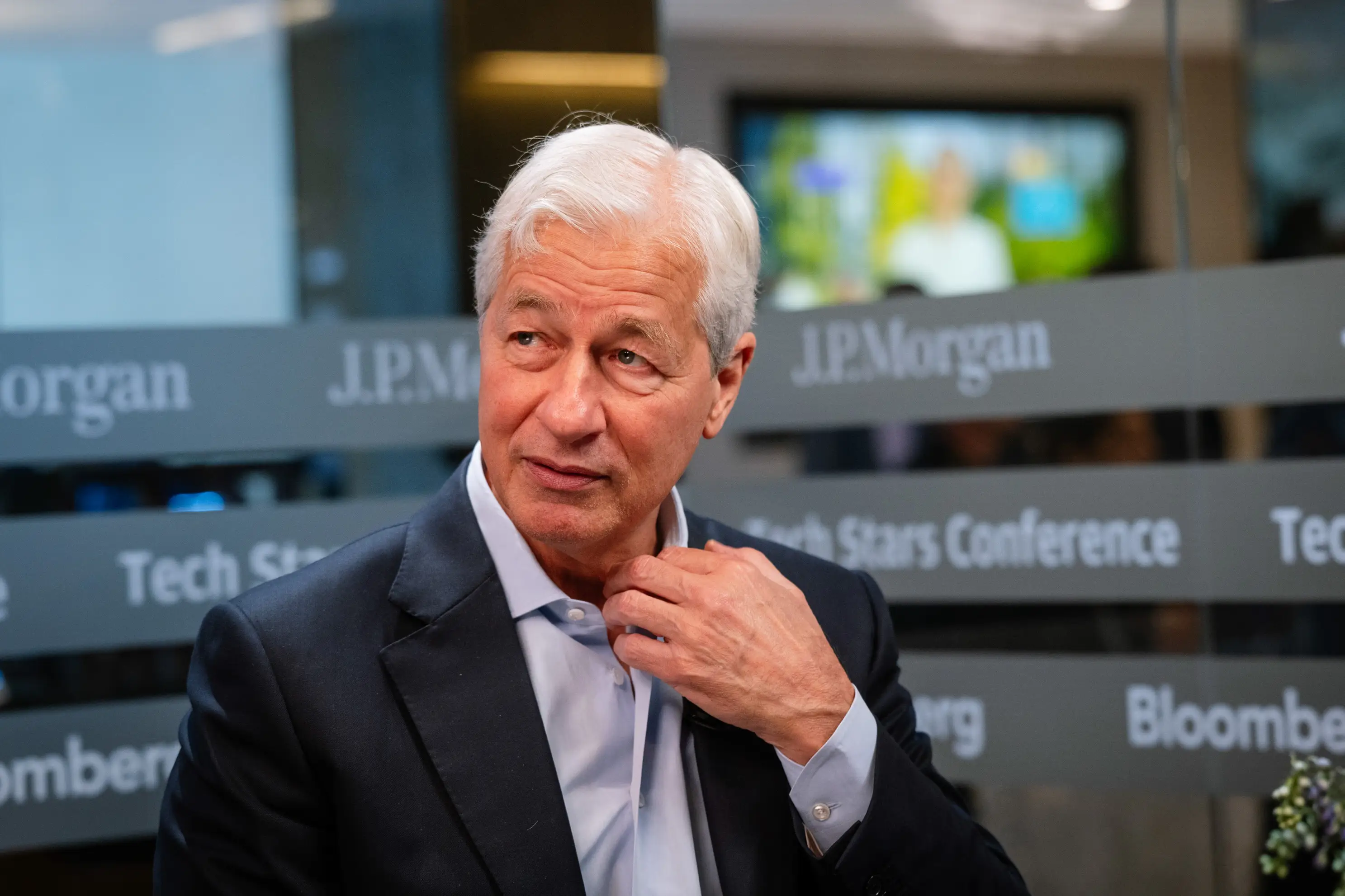 Jamie Dimon stands in front of JPMorgan banner
