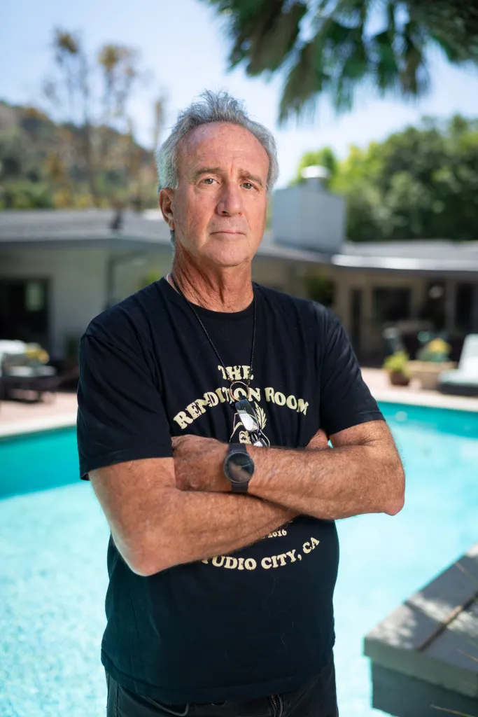 Matt Epstein, president of the Sherman Oaks Homeowners Association, standing outdoors in front of a pool, with his arms crossed.