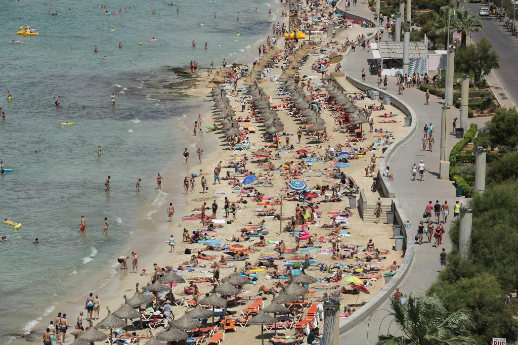 Visitors crowding the beach and promenade along the Ballermann stretch in Palma de Mallorca, Spain.