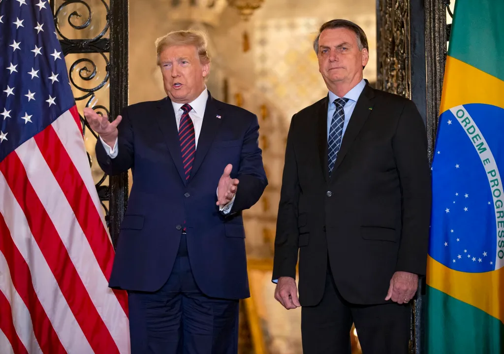 President Donald Trump and Brazilian President Jair Bolsonaro stand together with their national flags.