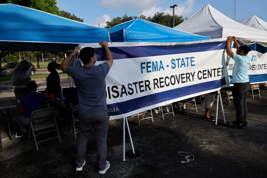 Two FEMA employees hanging a banner that says 