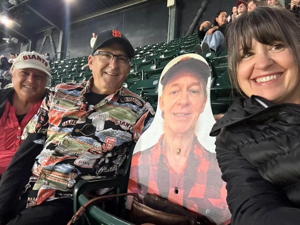 People at a San Francisco Giants game with a cardboard cutout of Steven Bassett.