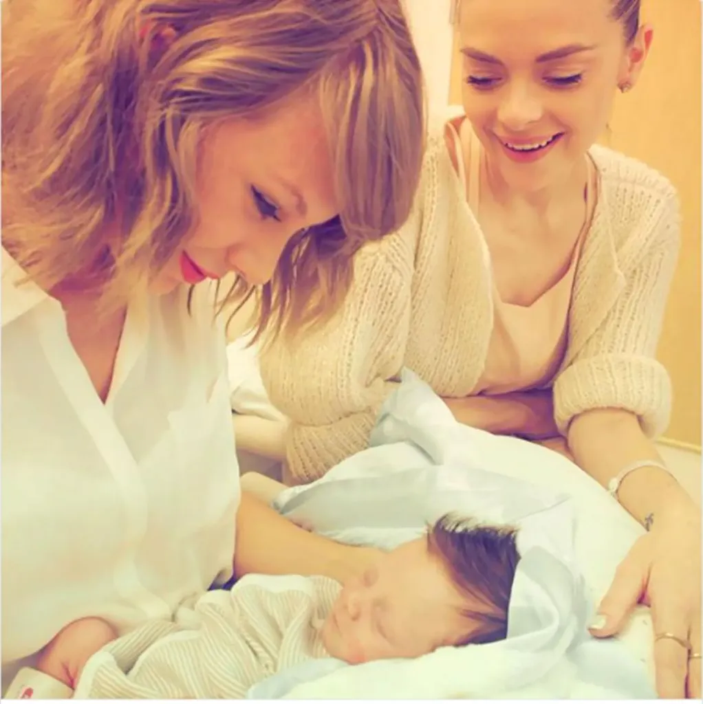 Taylor Swift looking at baby Leo Thames Newman with Jaime King.