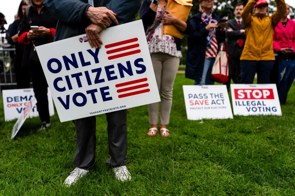 People holding signs at a rally, with one prominent sign reading 