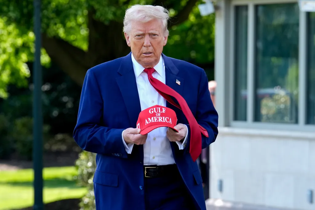Donald Trump holds a red baseball cap with 