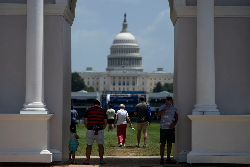 People seek shade under a replica of President Trump's planned 