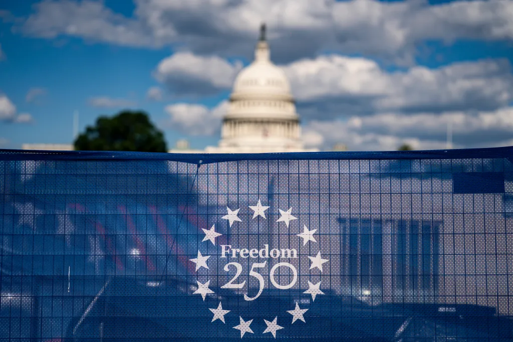 The US Capitol building stands behind a blue fence with the 