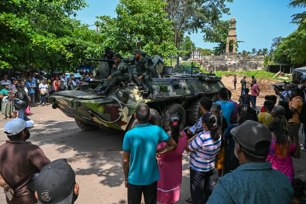Army officers stand guard on an armored vehicle outside Negombo prison after a riot.