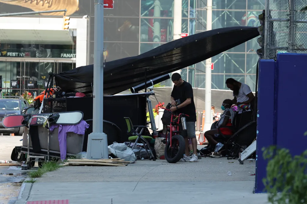 A homeless encampment with multiple individuals on a street in Midtown Manhattan.