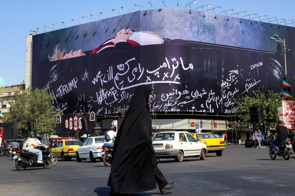 A woman walks past a giant anti-US billboard with a picture of Donald Trump in a coffin and text in Persian reading