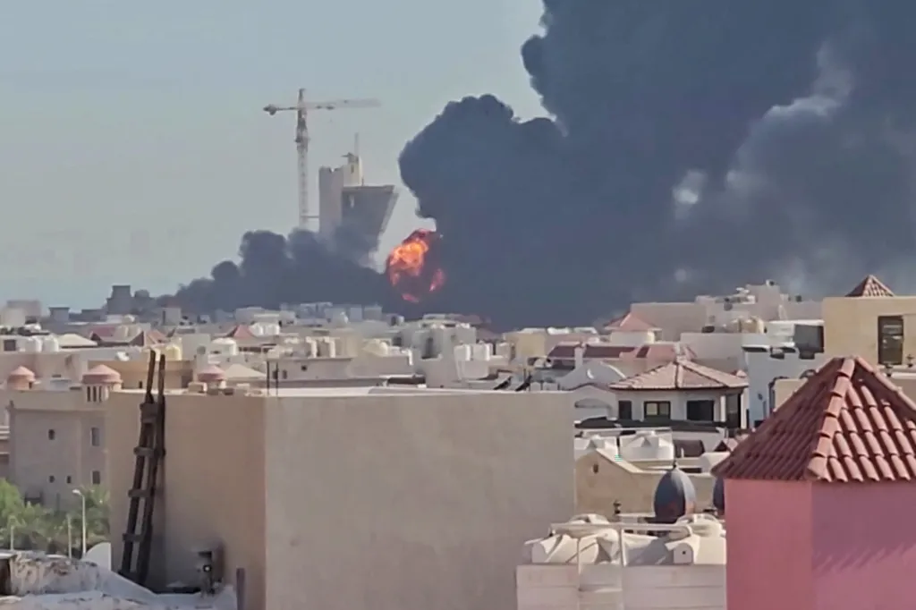 Thick black smoke and orange flames rise into the sky over buildings in Kuwait.