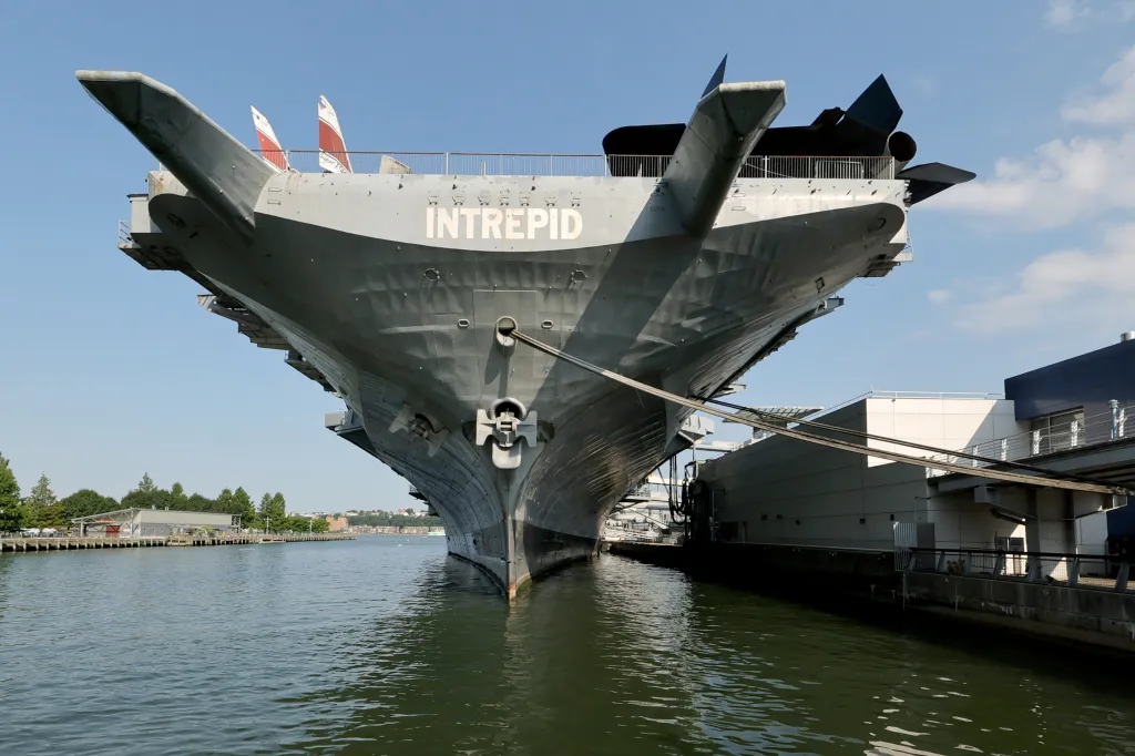 The USS Intrepid, a large gray aircraft carrier, docked on the West Side Highway in Midtown Manhattan.