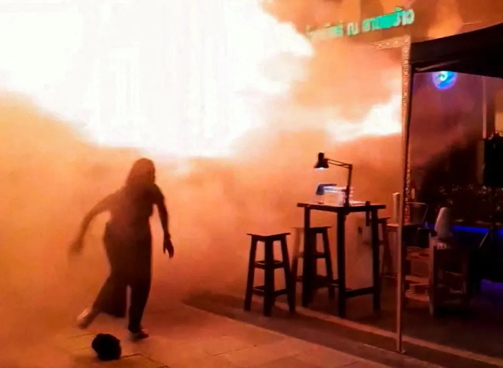 A person runs as flames rise at a pub in Bangkok, Thailand, in this screengrab taken from a social media video released July 13, 2026. 