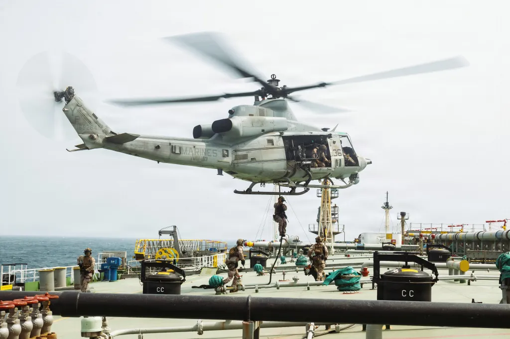 A military helicopter with U.S. Marines descending onto a ship during a boarding operation.