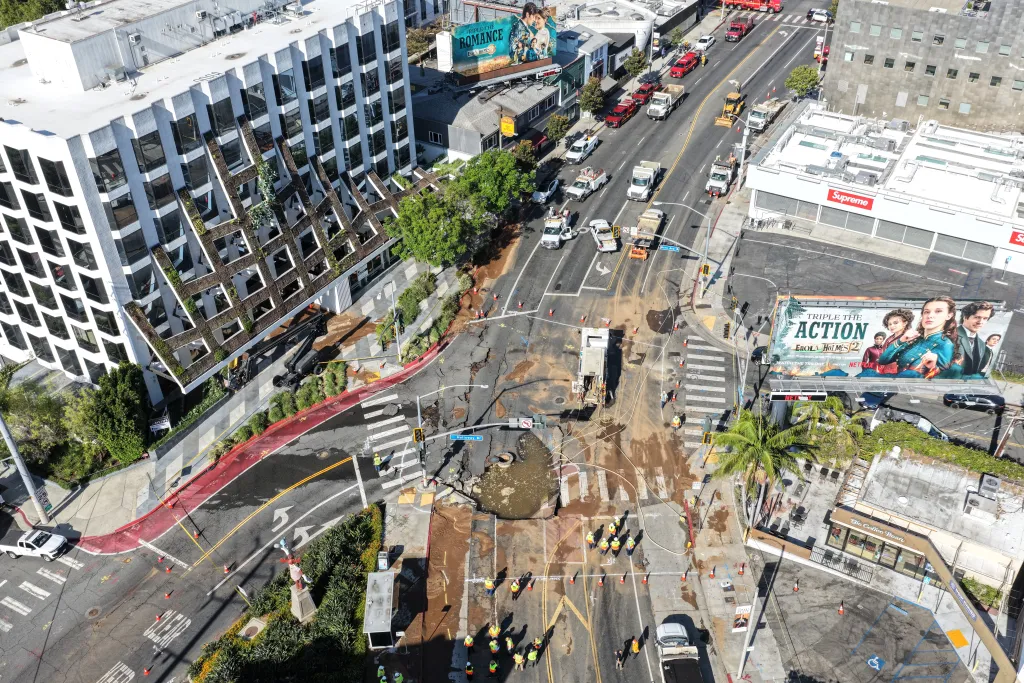Aerial view of utility repair workers at a sinkhole on Sunset Boulevard where a water main break flooded surrounding streets.