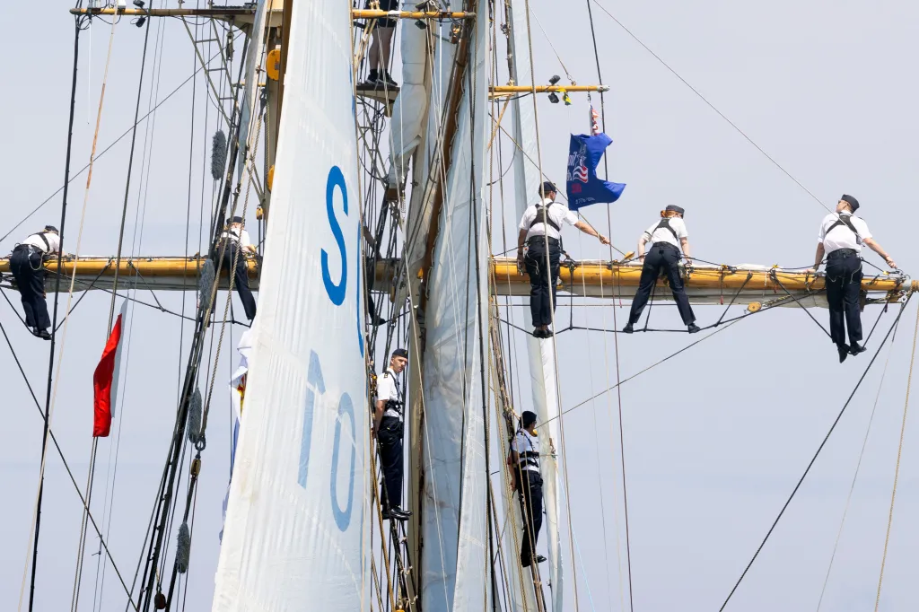 Crew members of the Swedish HMS Gladan schooner view the parade from the rigging.