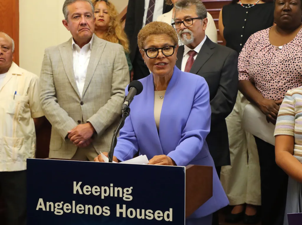 Karen Bass speaks at a podium with the text