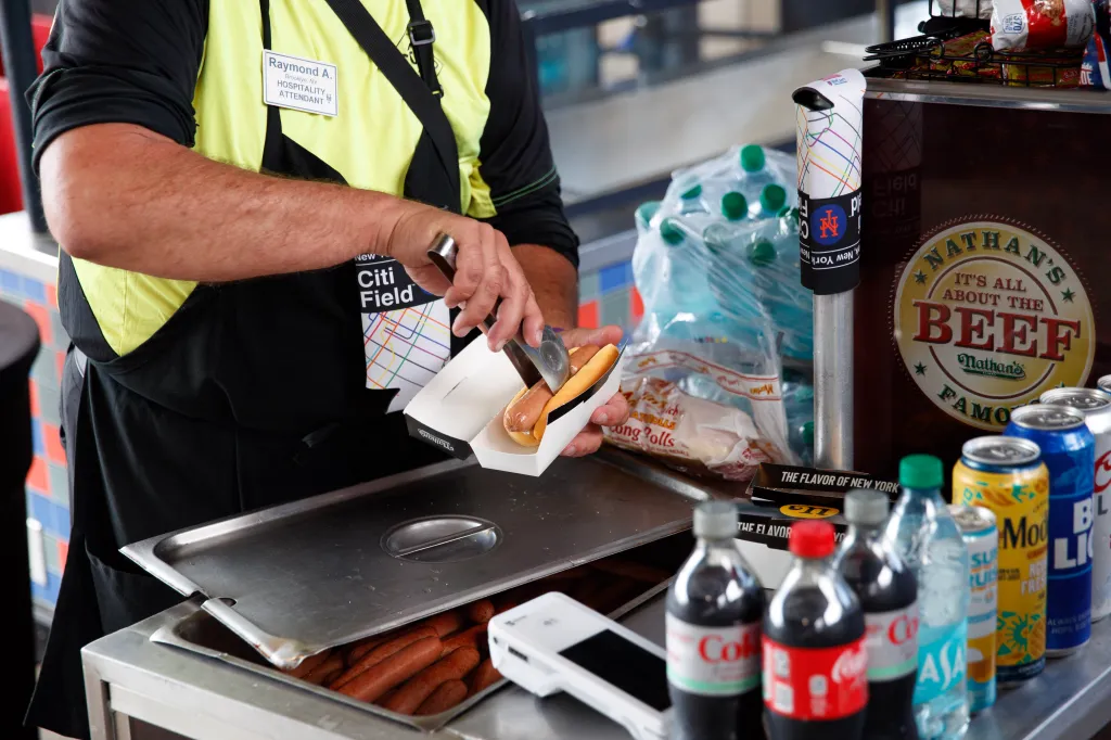 Raymond Acceta, a hospitality attendant, serving a hot dog in a box at Citi Field.