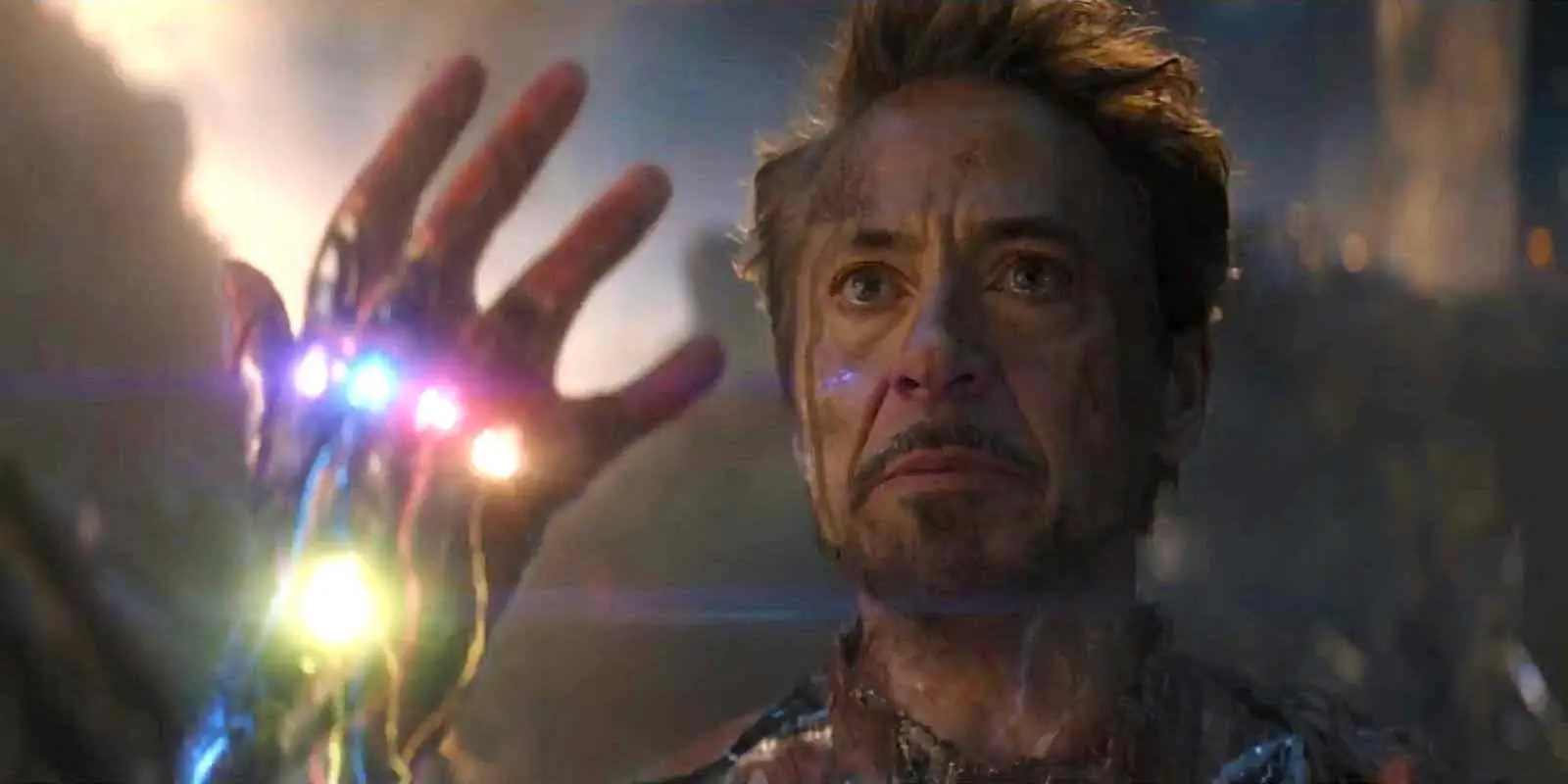 Robert Downey Jr. as Iron Man, holding up a gauntlet with six stones, in 