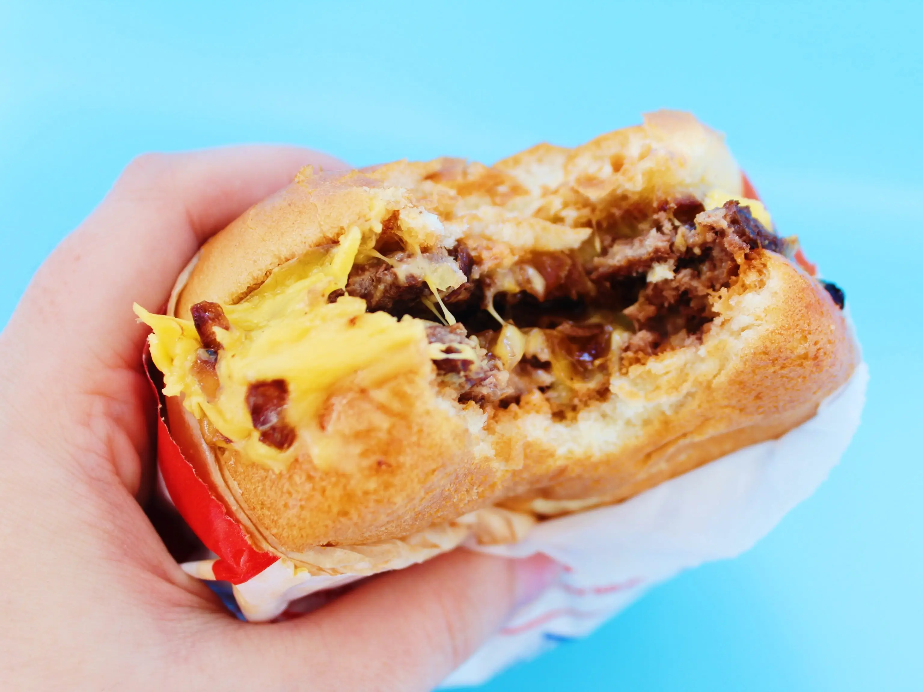 bitten into in n out double double on blue background