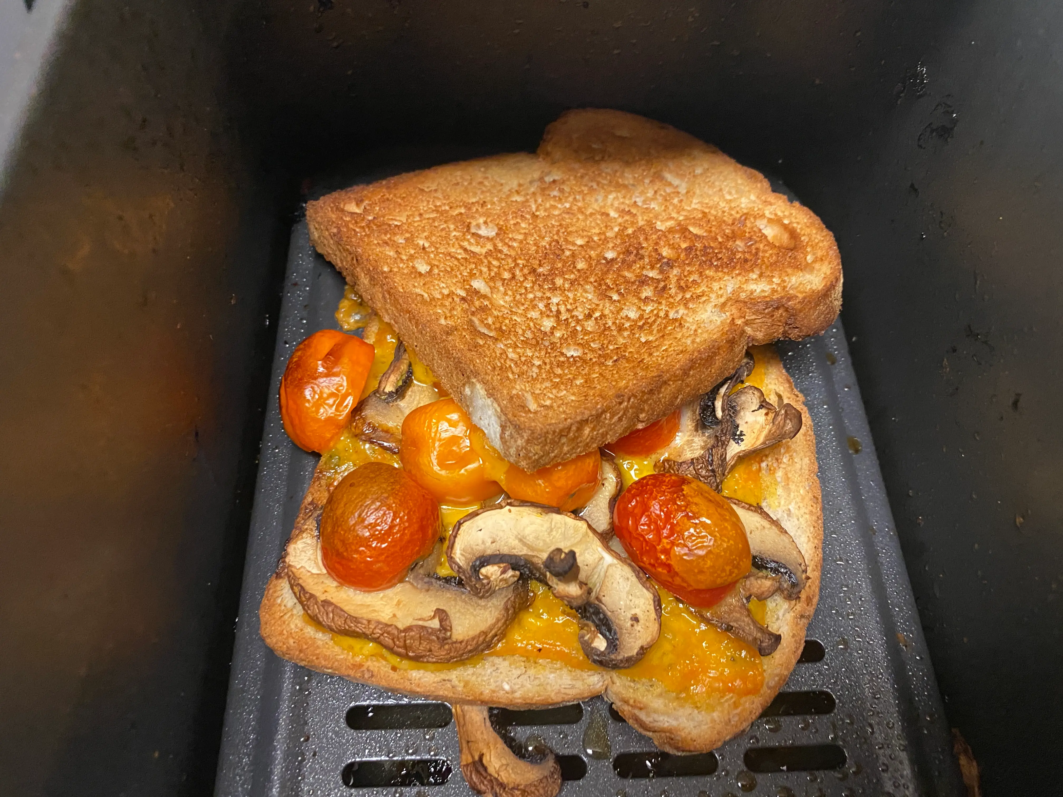 pesto, sliced cherry tomatoes, and mushrooms on bread in an air fryer