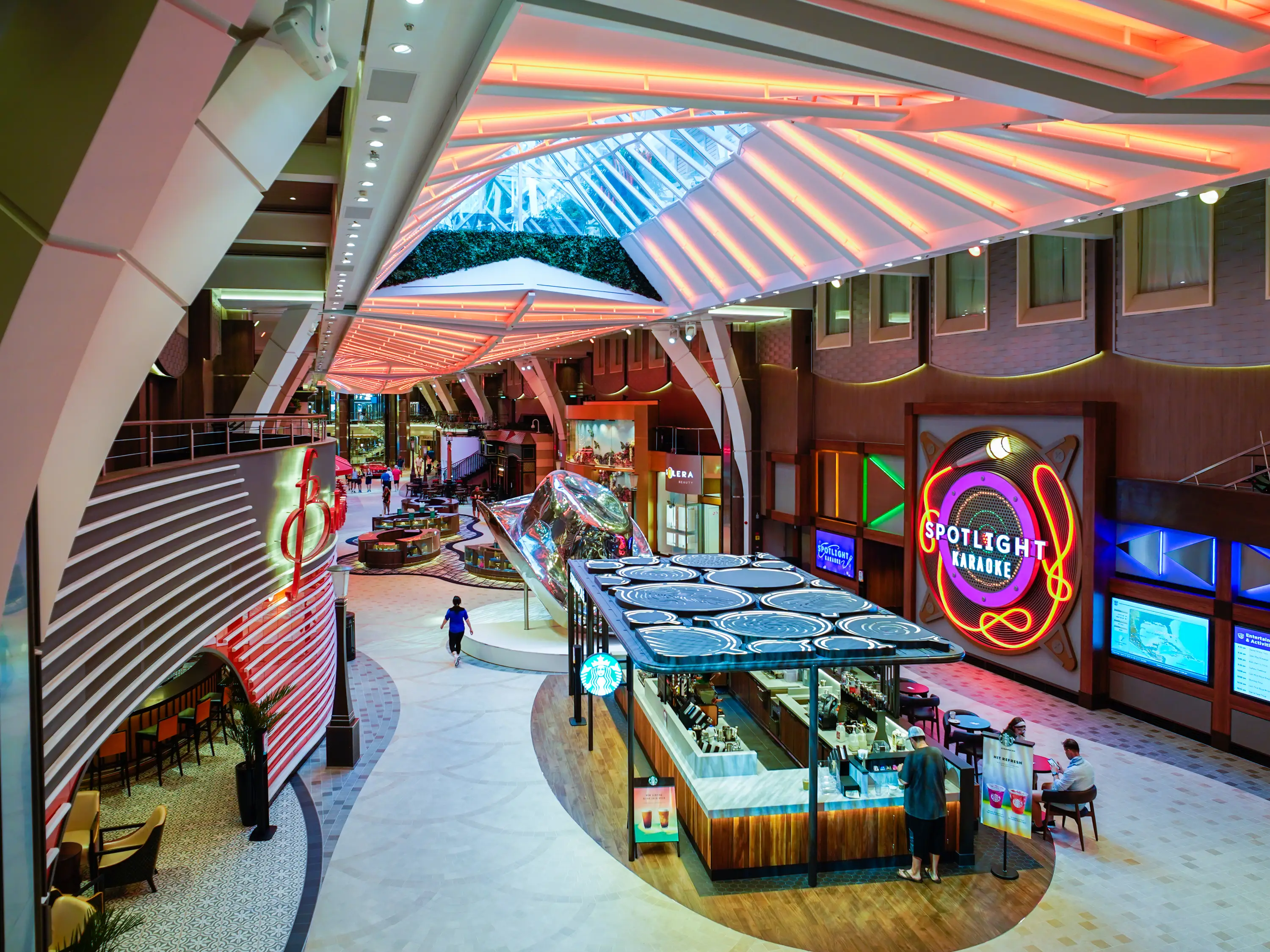 An indoor cruise ship deck with shops and restaurants