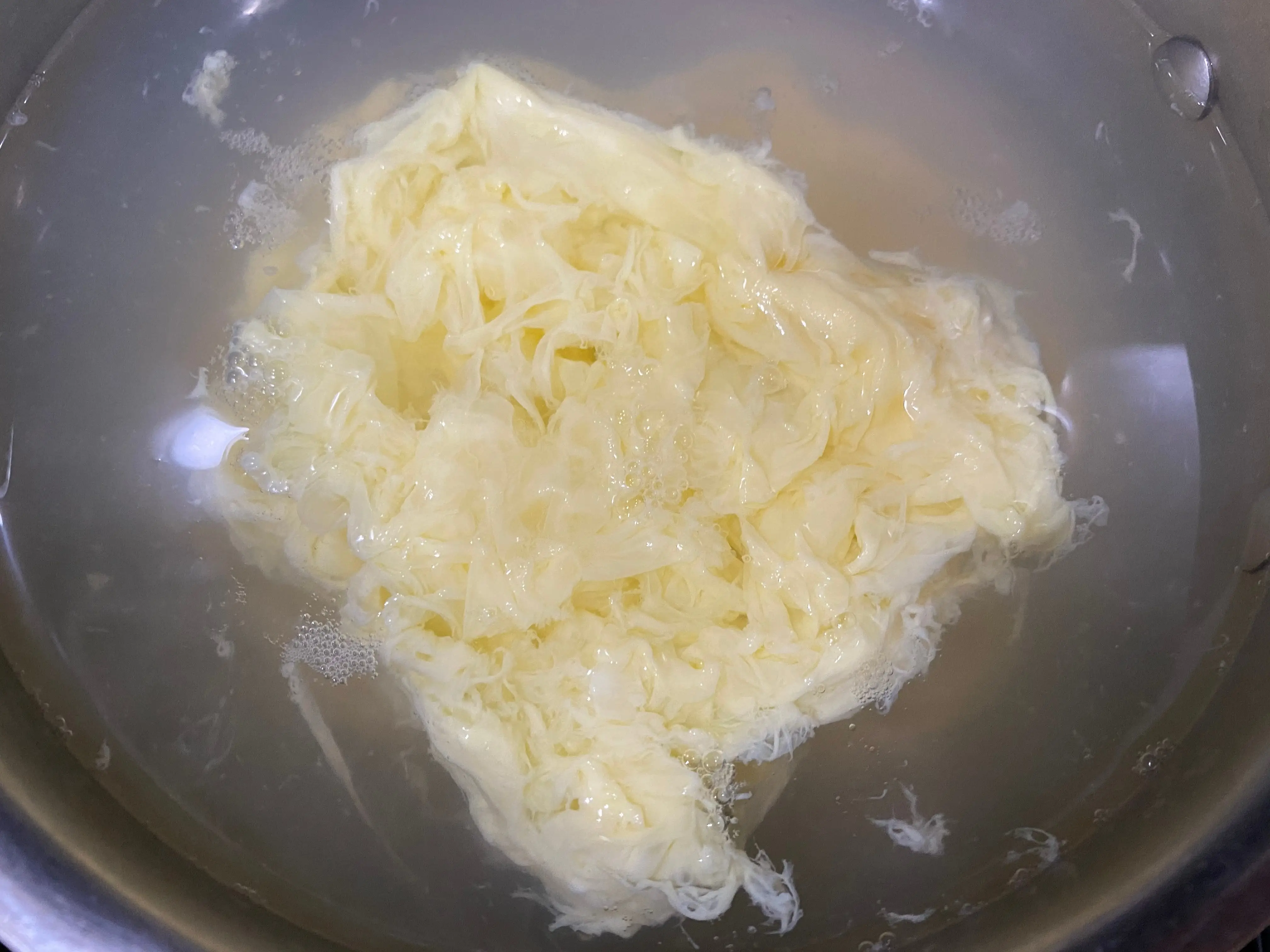 Ribbons of scrambled eggs in a pot of boiling water with a lid