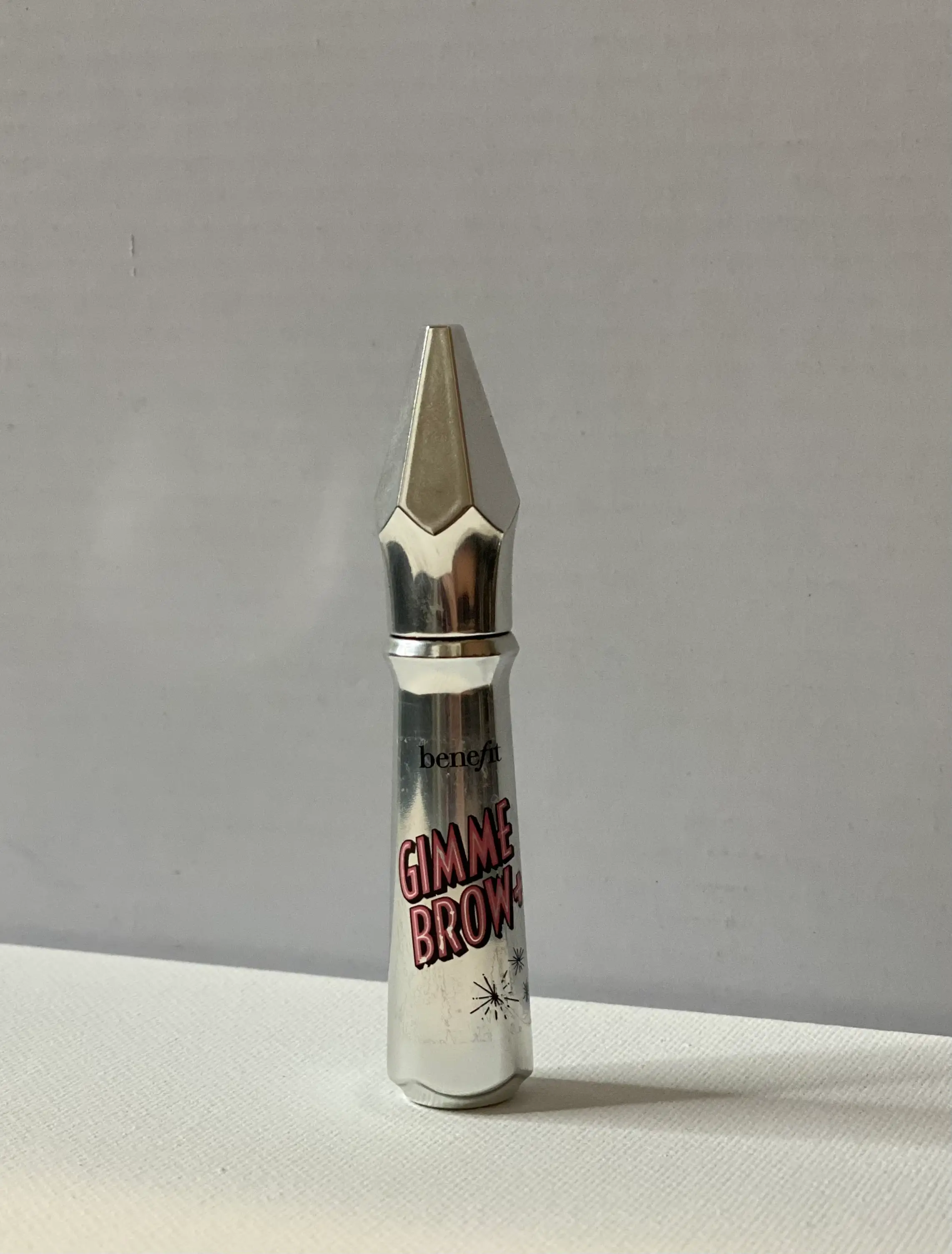 A metal Benefit brow product with pink 