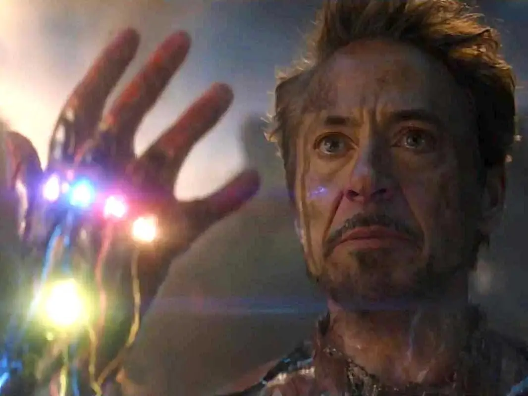 Robert Downey Jr. as Iron Man, holding up a gauntlet with six stones, in 