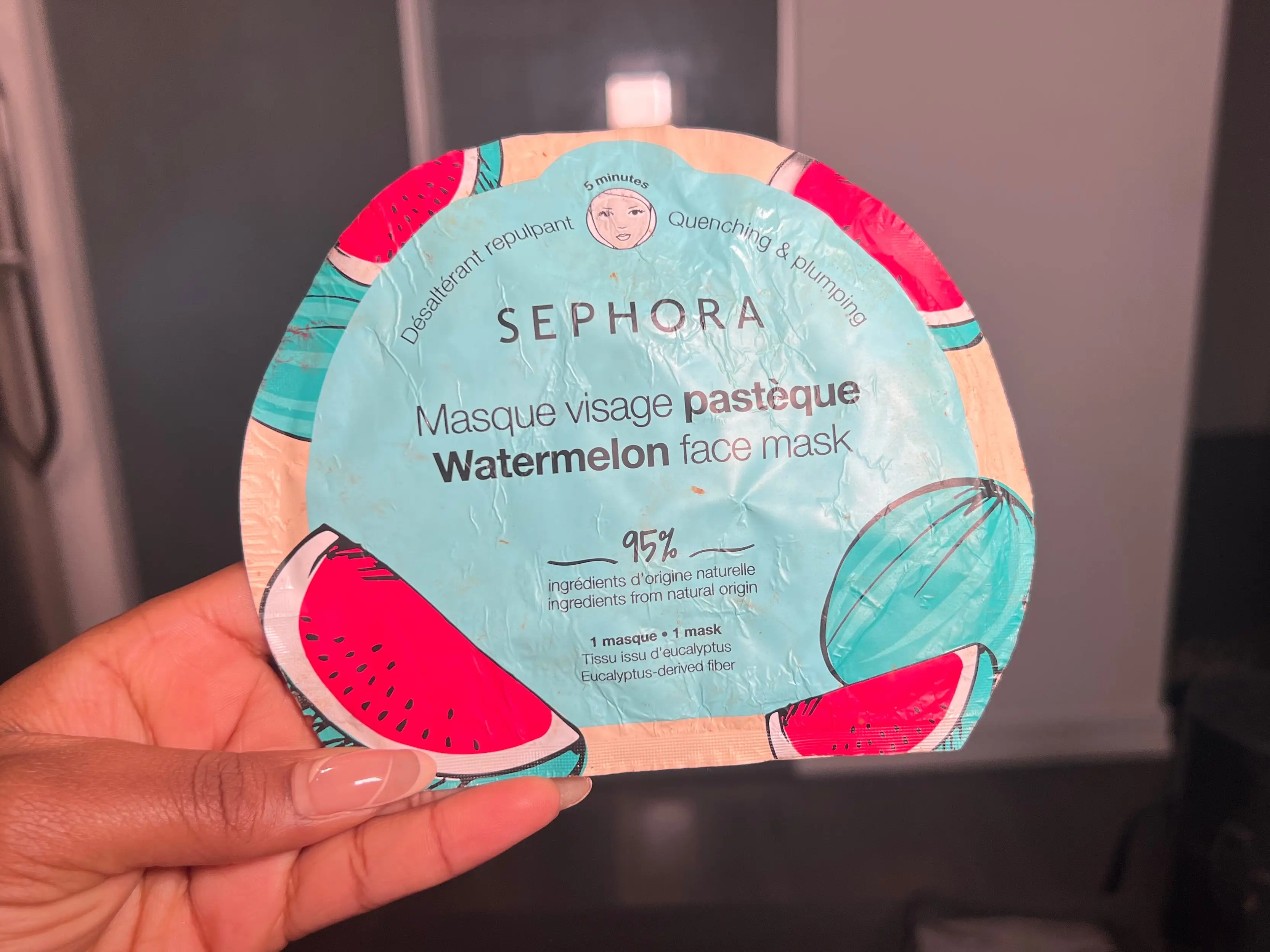 The writer holds a blue and red sheet mask with a watermelon illustration on the front