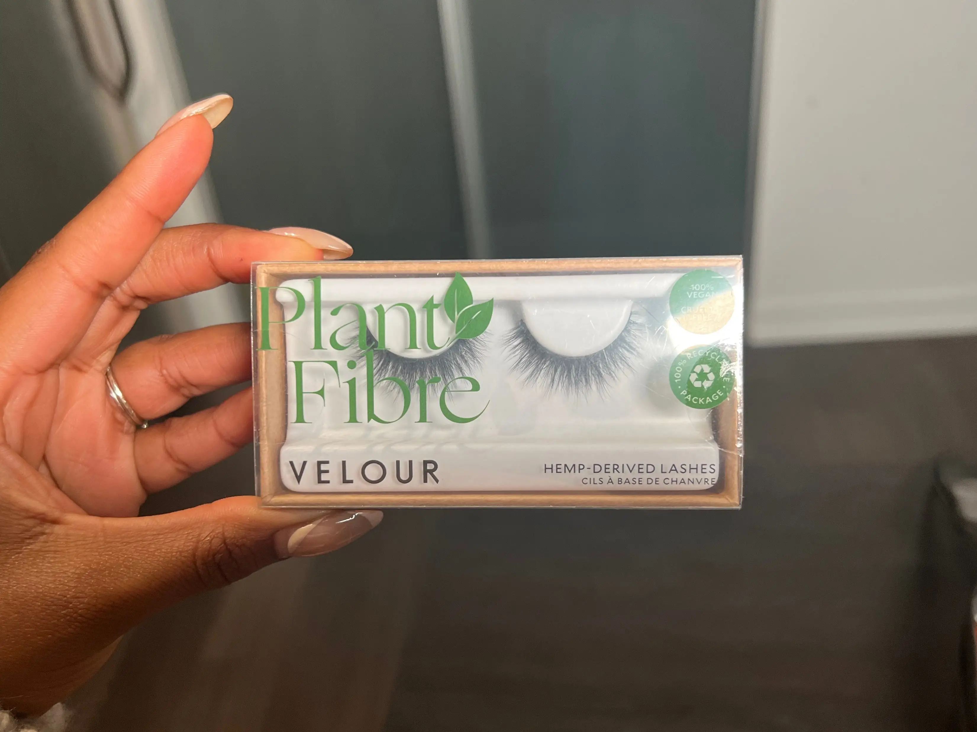 The writer holds a package with false lashes with green text saying