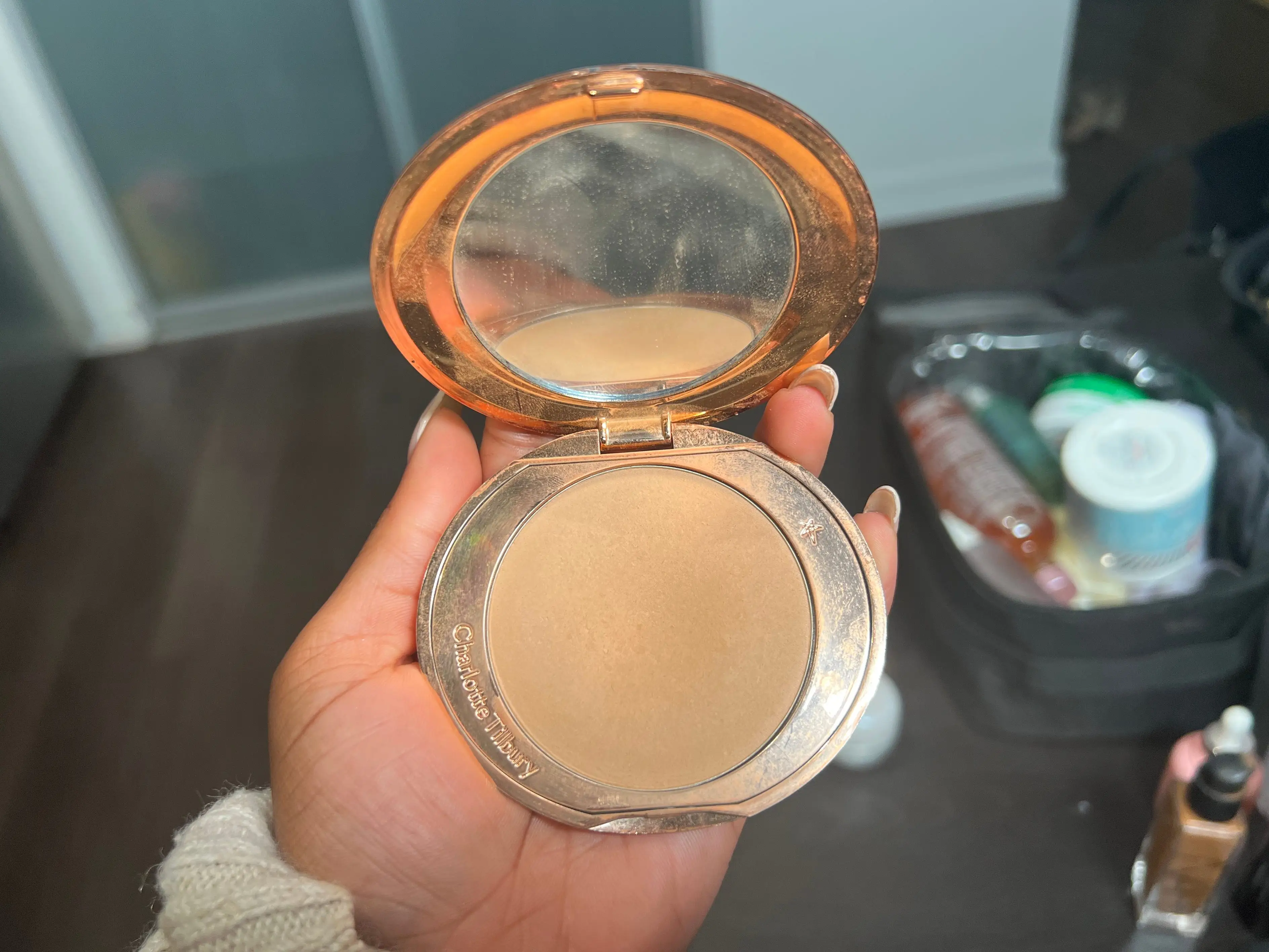 The writer holds a compact with a tan powder and a mirror