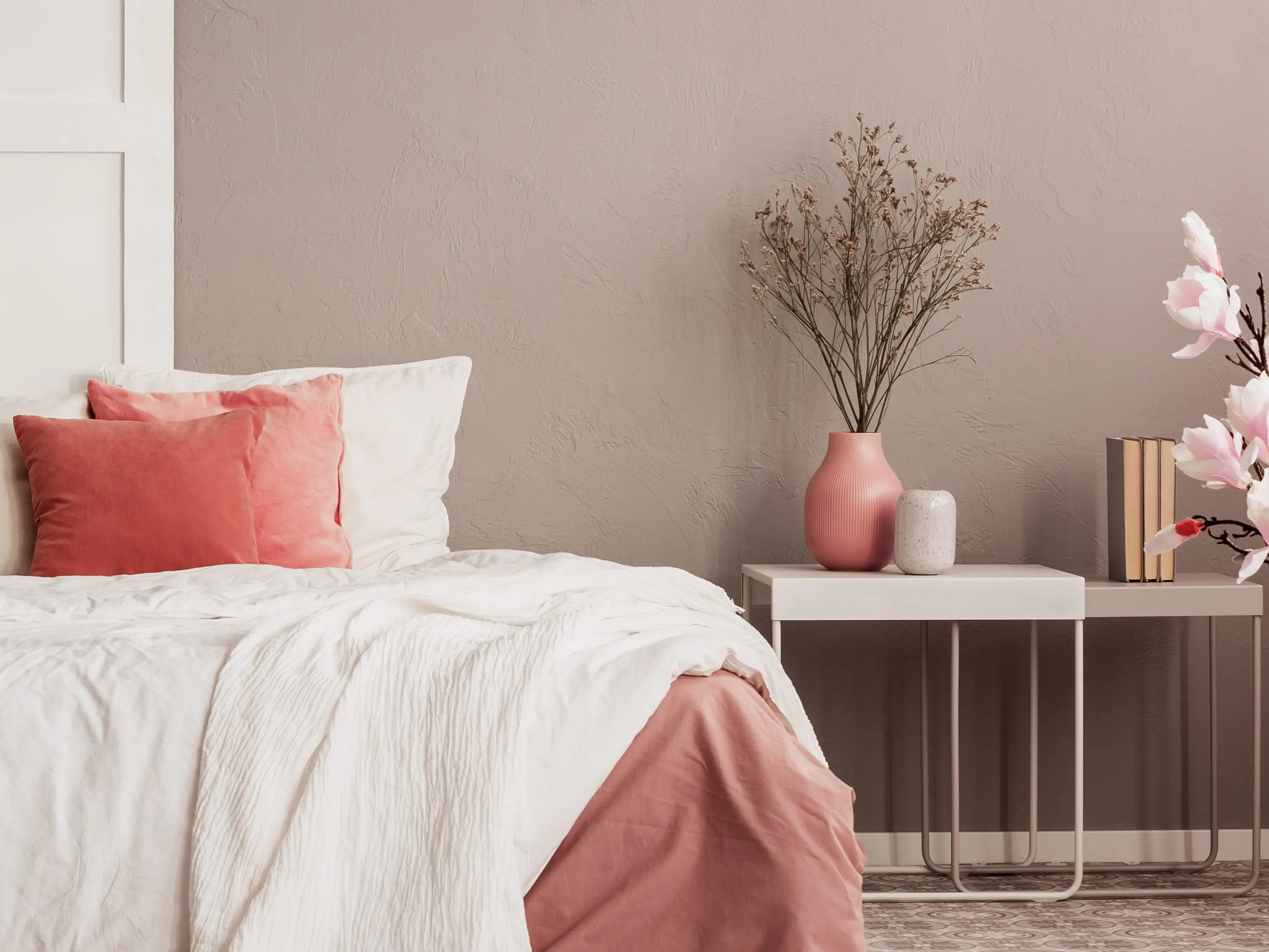 Pink and white bedding on bed with a white nightstand next to it