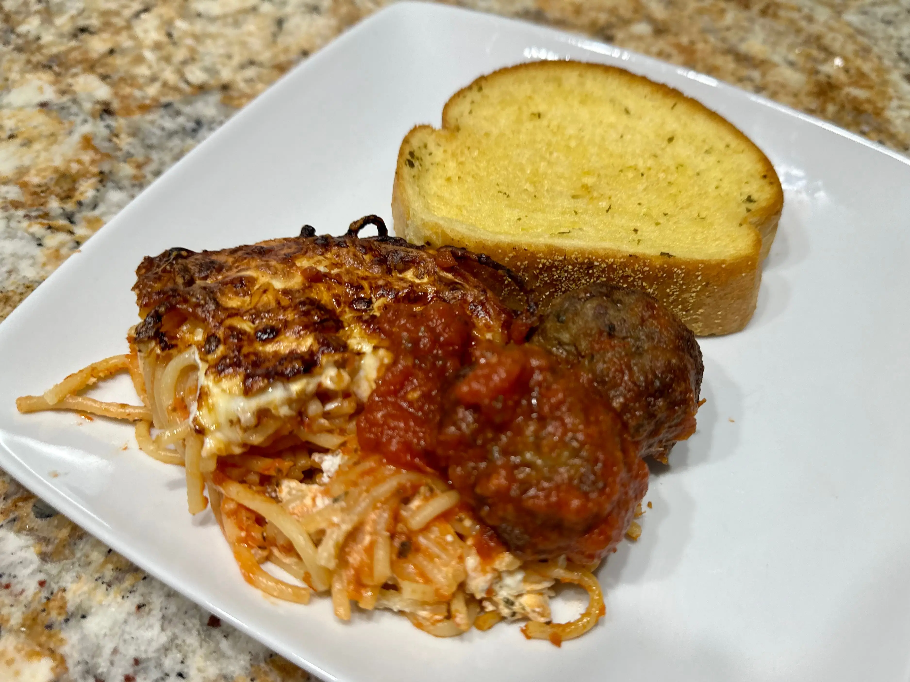 Spaghetti, meatballs, and garlic bread on a plate.