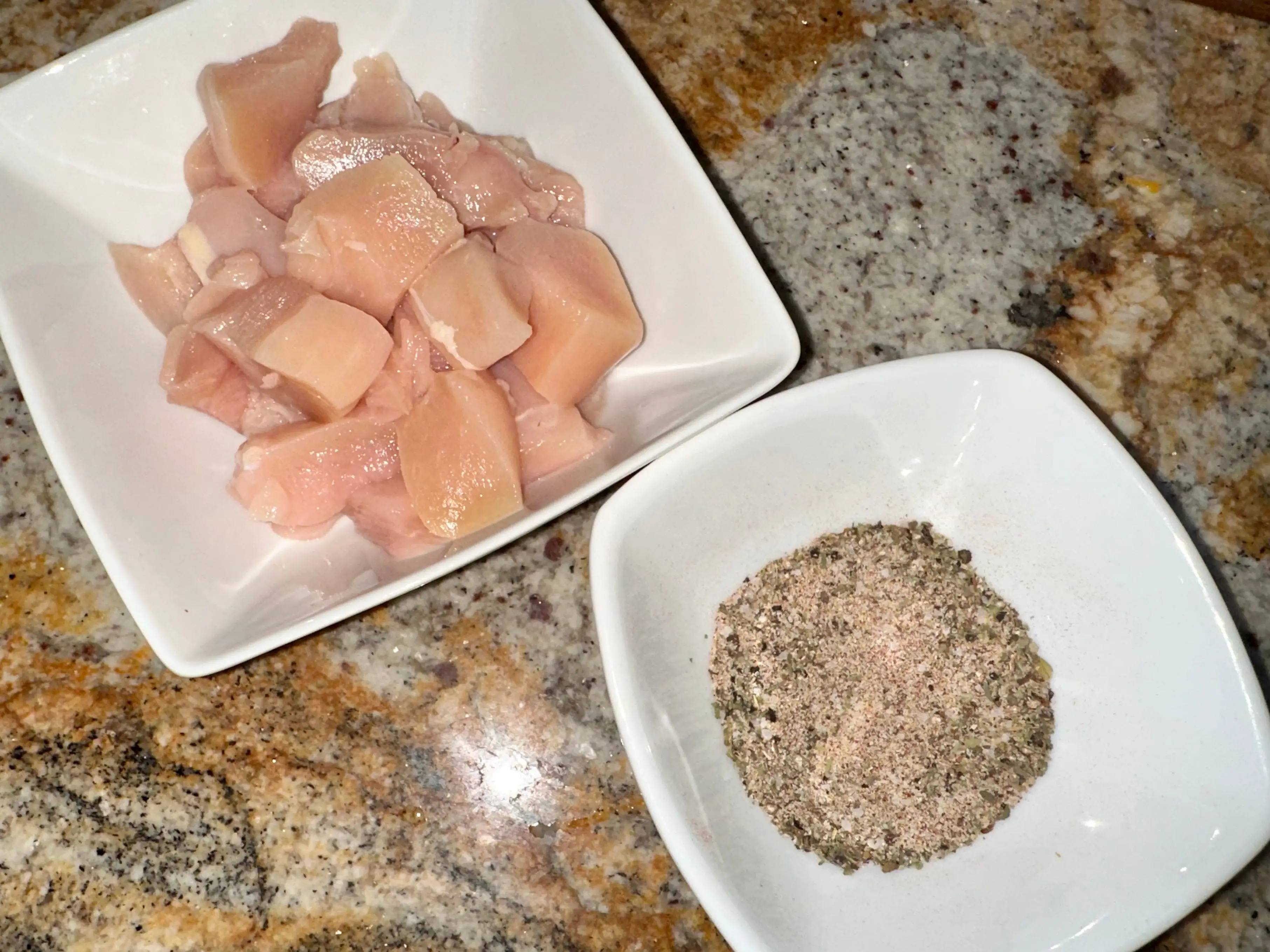 Raw chicken and spices in separate bowls.